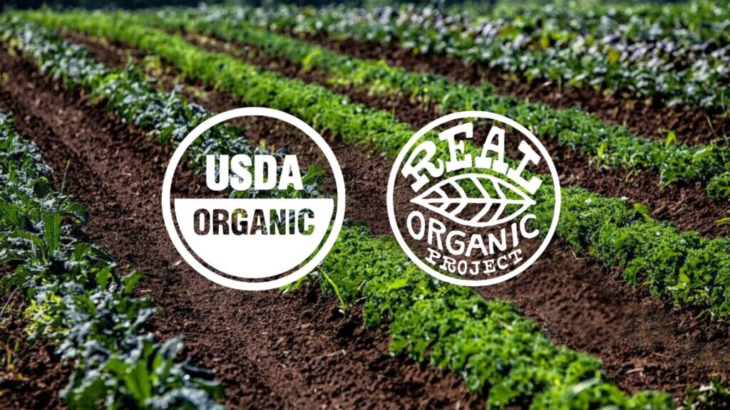 The USDA Organic Seal and the Real Organic Project Seal against a row of crops.